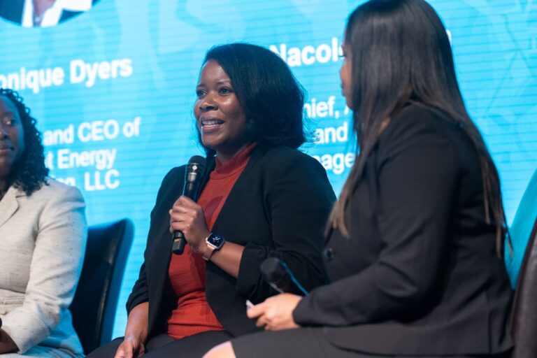 A woman talks into a microphone on a stage.