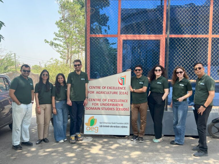 Eight people pose next to the Centre of Excellence for Agriculture.
